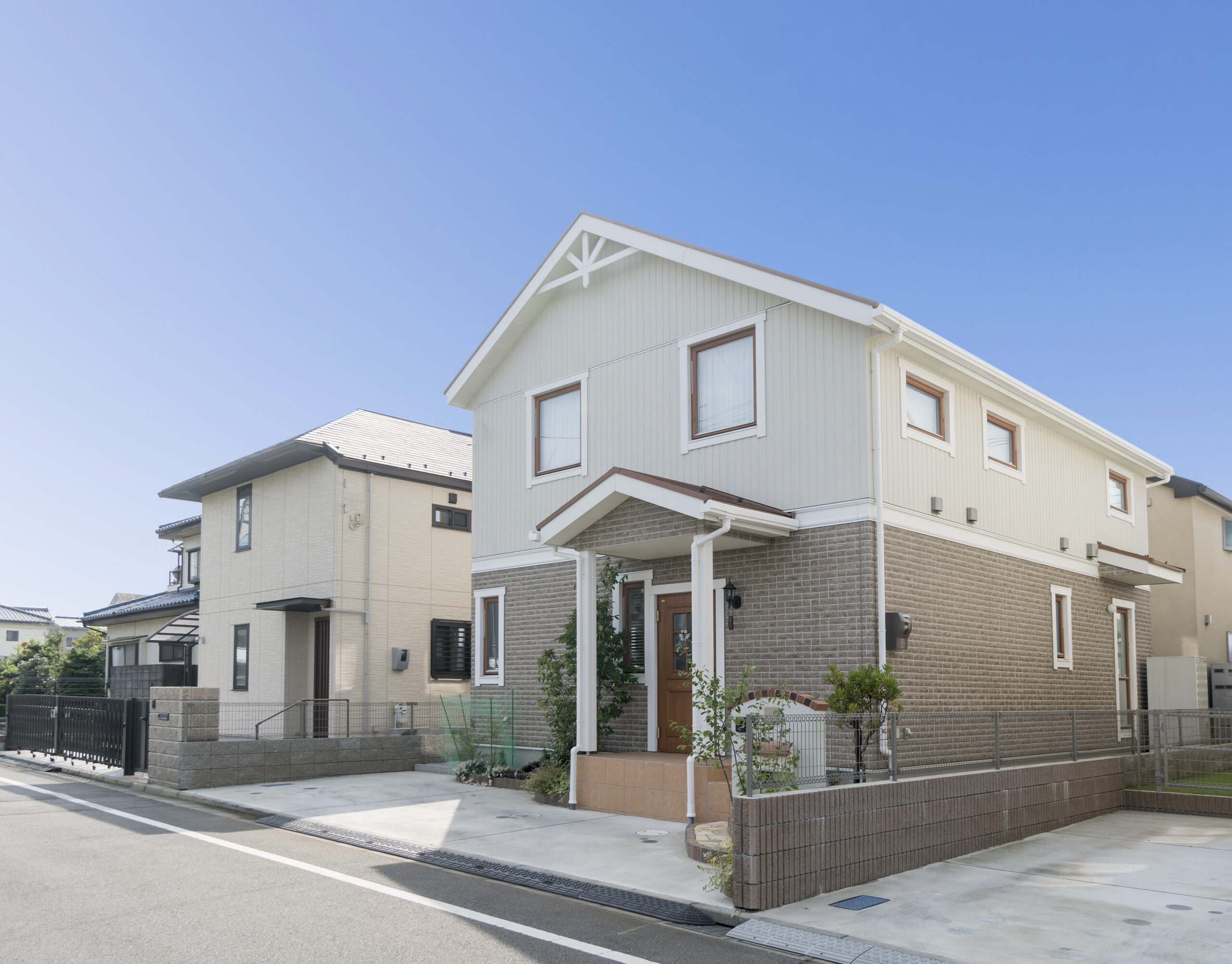 青空の下に建つ、完成した二階建て住宅の外観